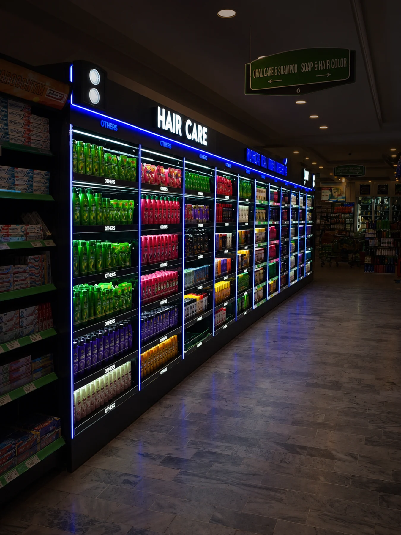 Long illuminated hair-care category aisle with blue bay dividers